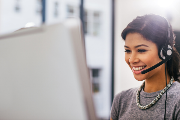 woman wearing headset looking at computer screen in the foreground 
