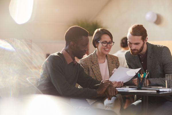 three people seated together looking at paper in right corner