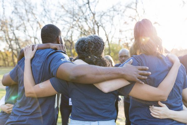 three people from behind with arms around each other