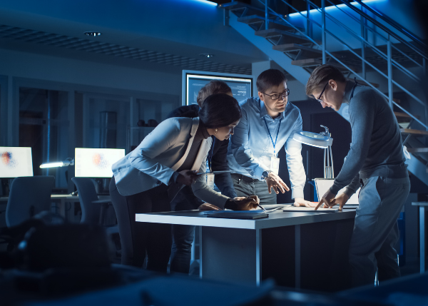 three people working together in darkened office space