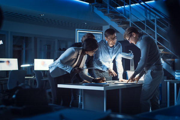 three people working together in darkened office space