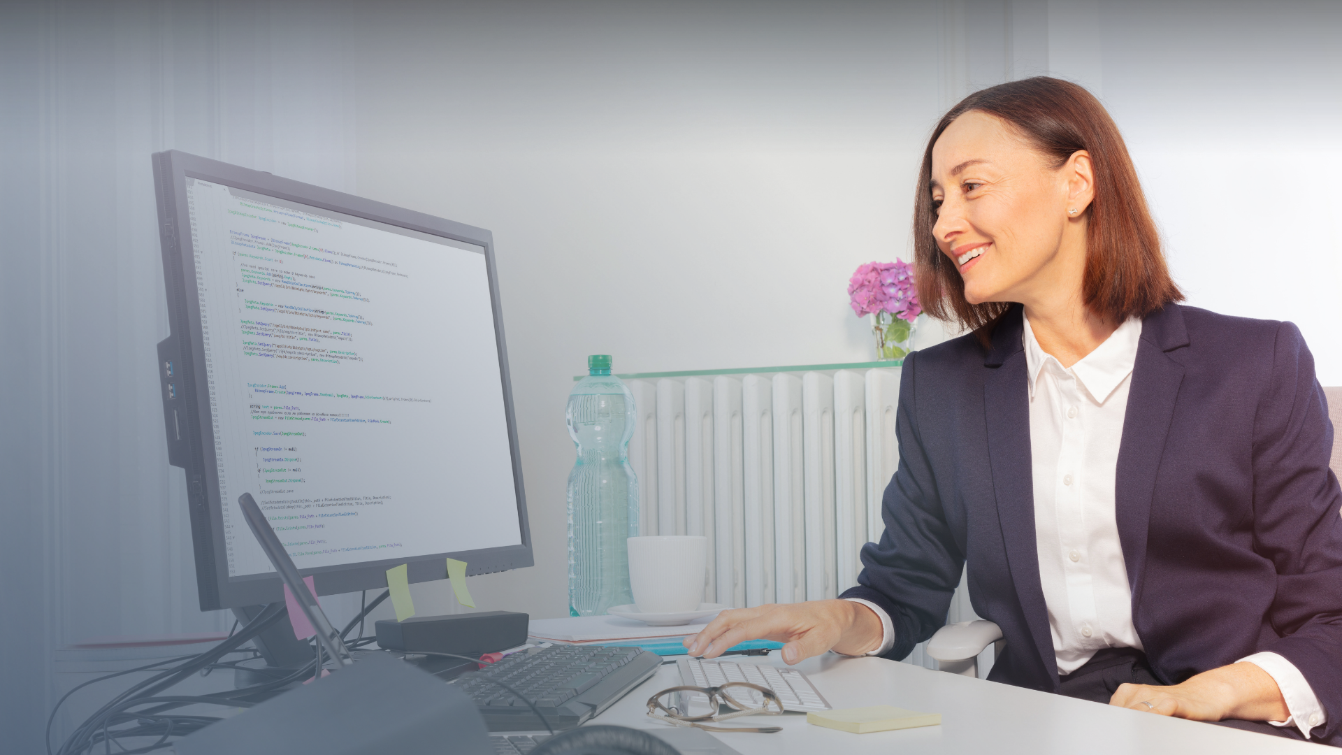 Business woman smiling and looking at code on her monitor