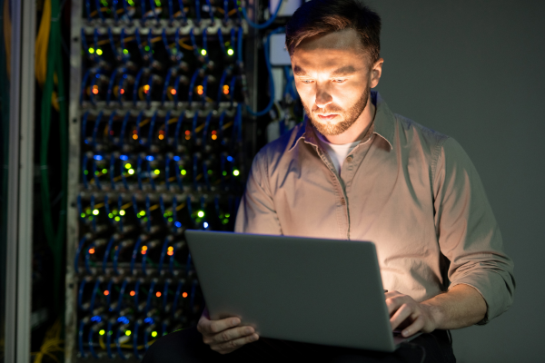 person seated in front of data machine with laptop lighting up face