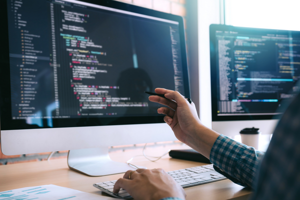 person pointing to code on computer screen