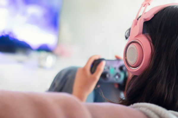 close up over the shoulder of woman wearing headphones and holding video game controller