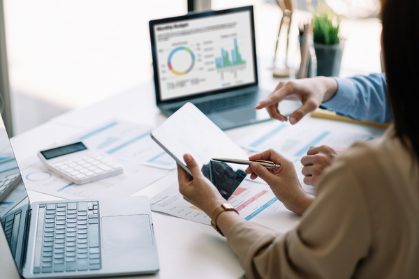 two people working at desk with dashboard graphics on computer