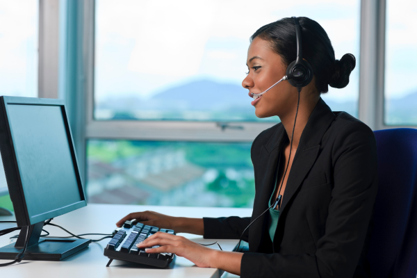 woman sitting at desktop computer wearing headset