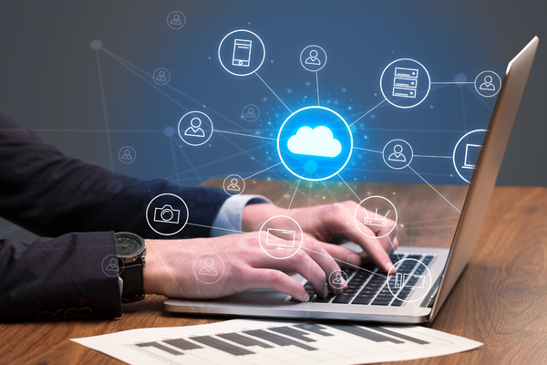 hands typing on laptop with interconnected cloud and business icons