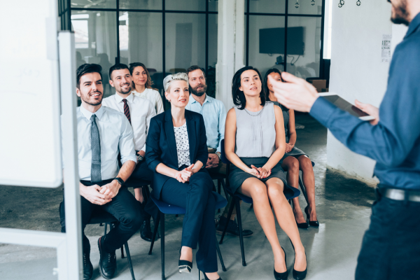 group of professionally dressed people seated and watching a speaker