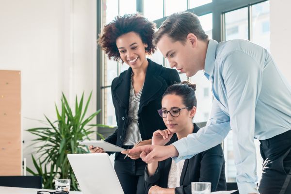 Two women and a man collaborating over a laptop