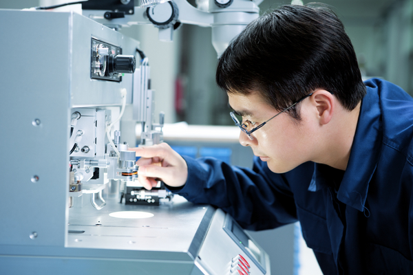close up image of man looking at machinery in lab setting