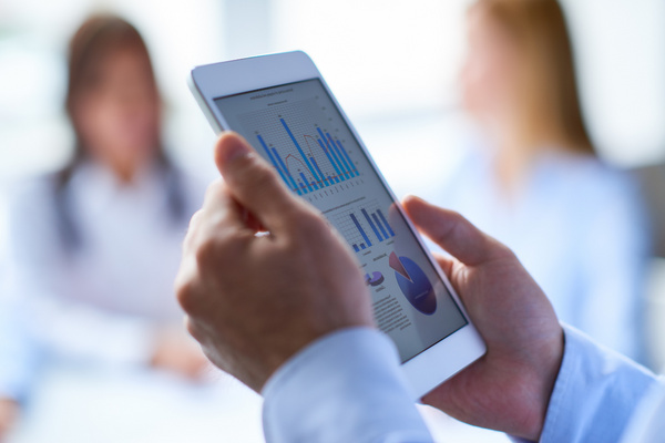 close up of hands holding a tablet with charts and graphs