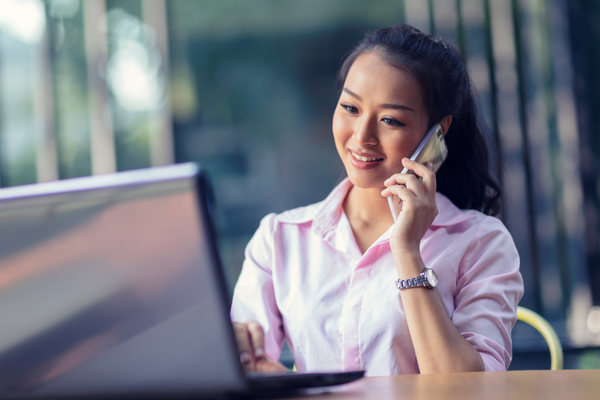 woman at laptop talking on phone