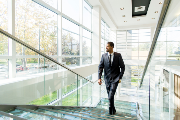 professionally dressed man walking up modern looking staircase 