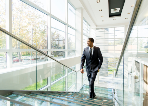 professionally dressed man walking up modern looking staircase 