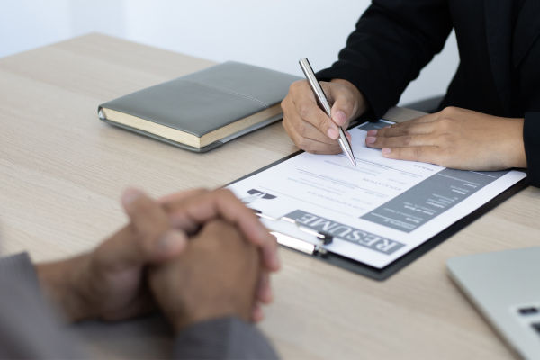 close up on hands of two people across from each other with resume on table 