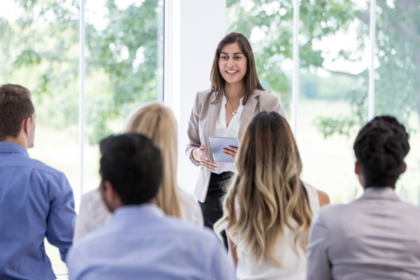 group of people watching woman speak