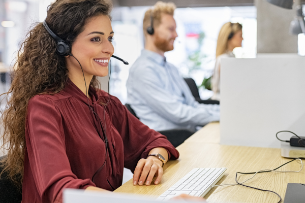 Woman with headset on at computer in a call center.