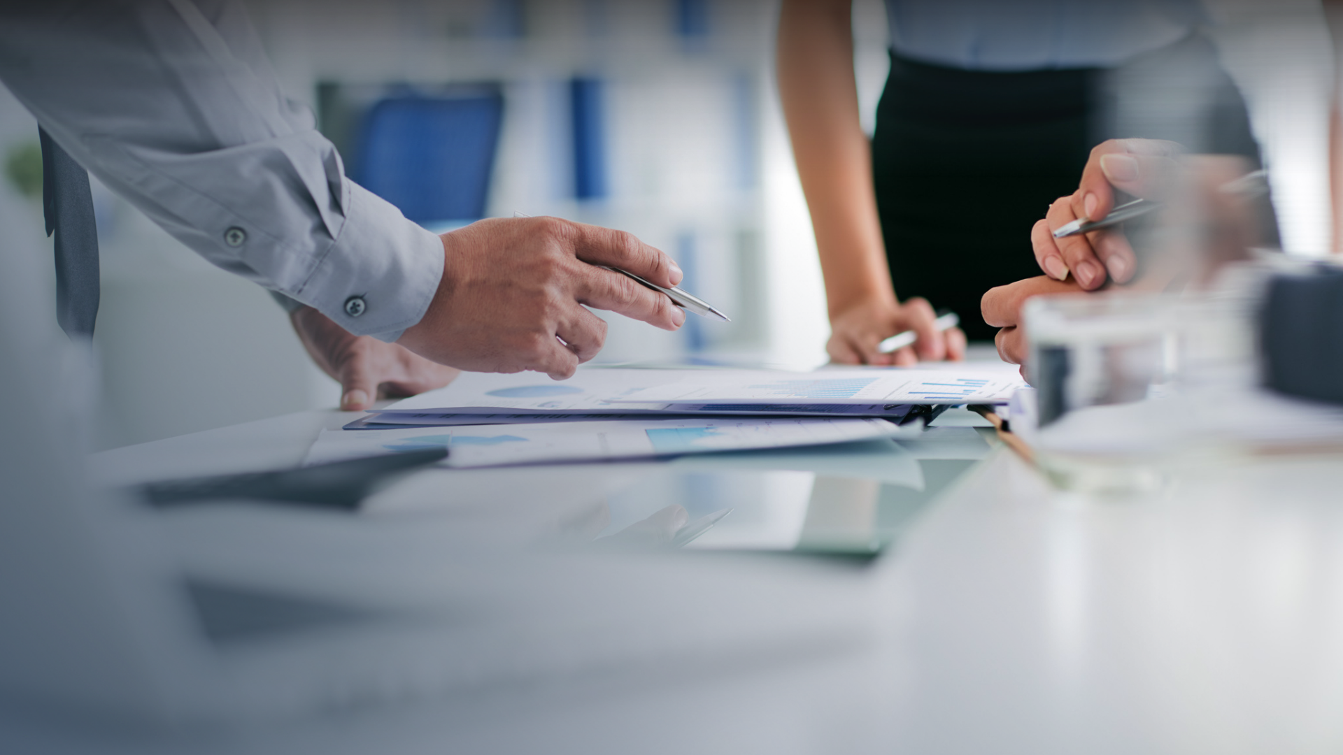 Employees hand pointing at graphs and charts on desk