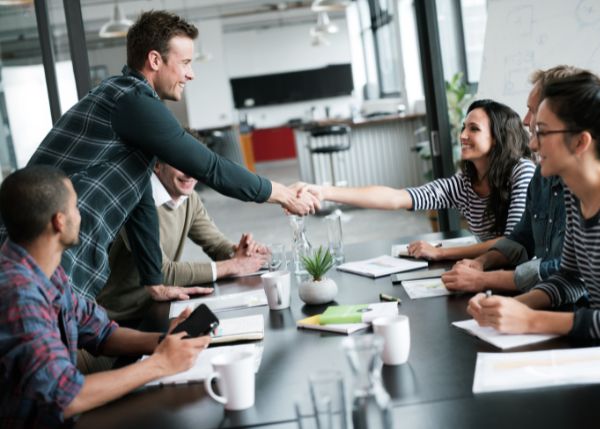 A man and a woman shaking hands across a table
