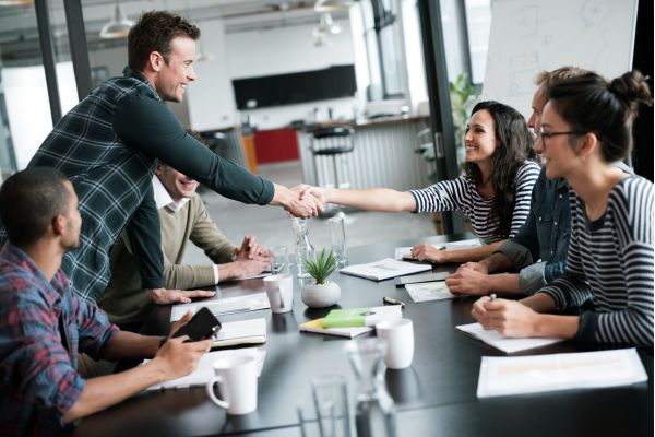 A man and a woman shaking hands across a table