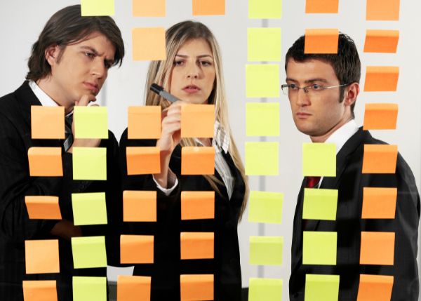three people organizing a process with post-it notes