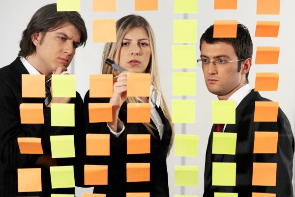 three people organizing a process with post-it notes