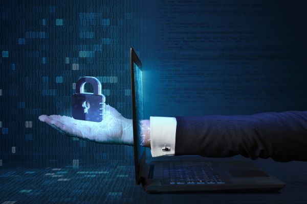 A hand reaching through a laptop holding a lock