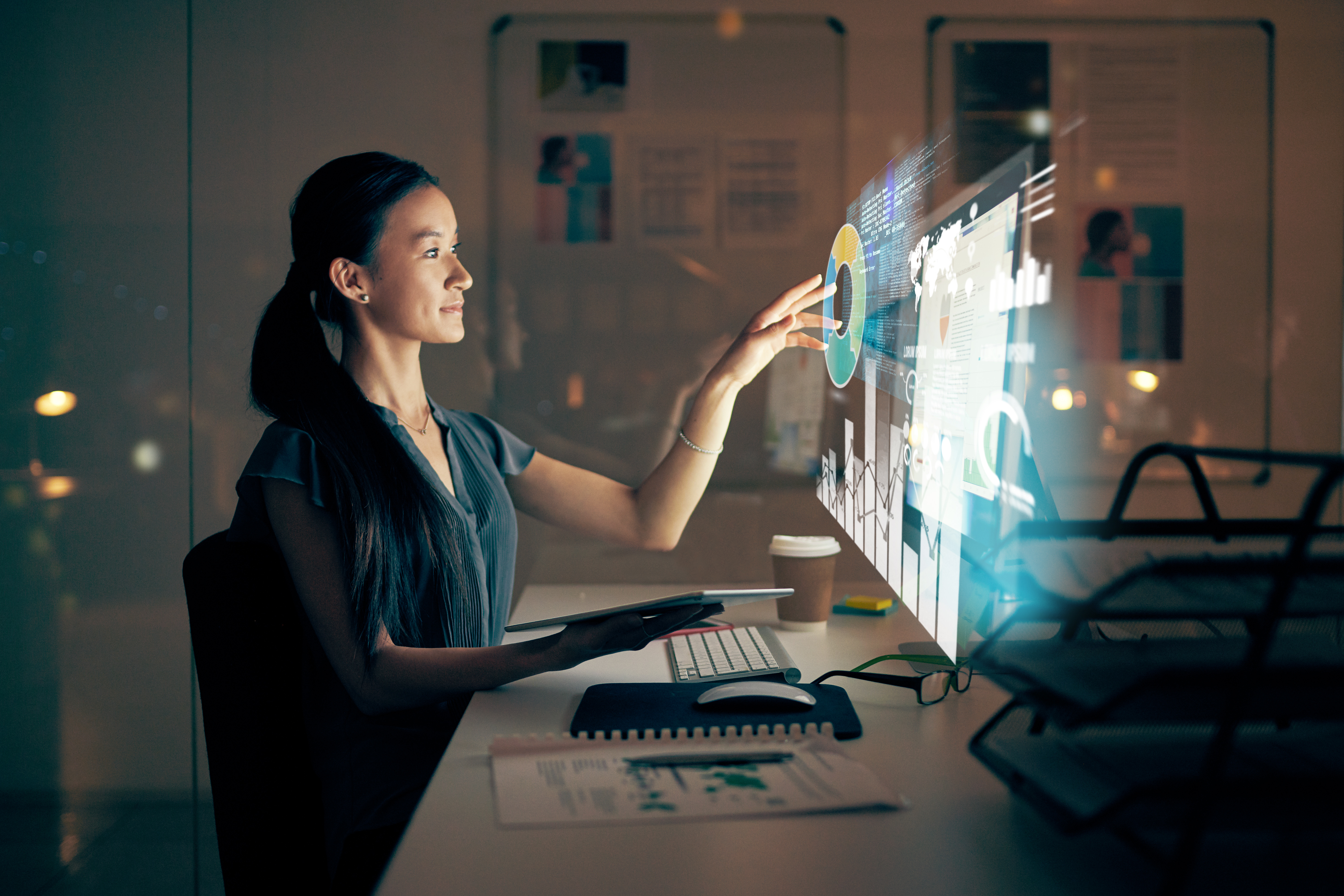 Woman sitting at desk, hand on monitor extracting AI display