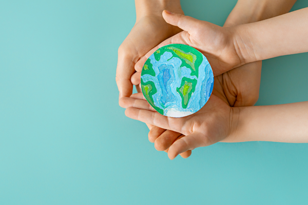 Mint background with an earth being held within an adult and childs hands
