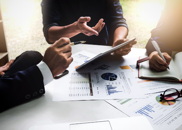 Three professionals working at desk with analytic graphs and charts