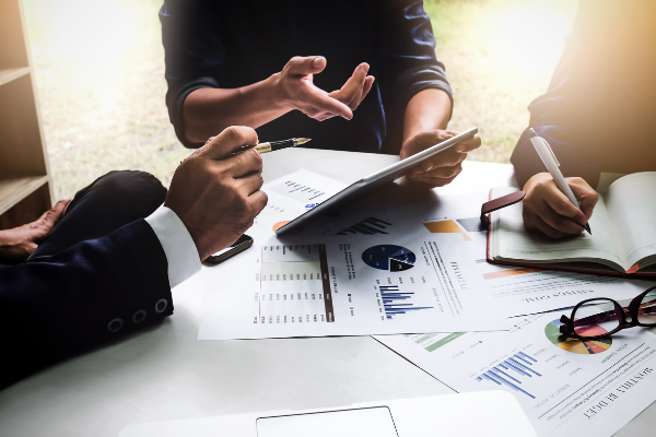 Three professionals working at desk with analytic graphs and charts
