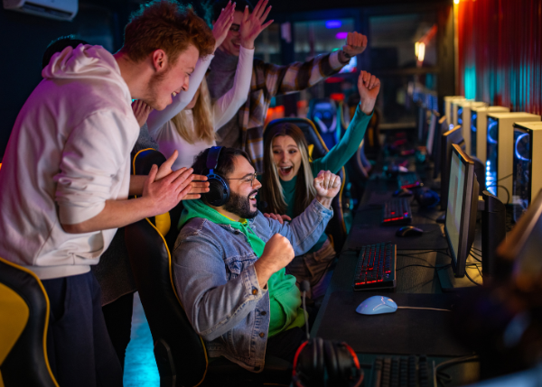 Gamers cheering in celebration together surrounded by gaming stations
