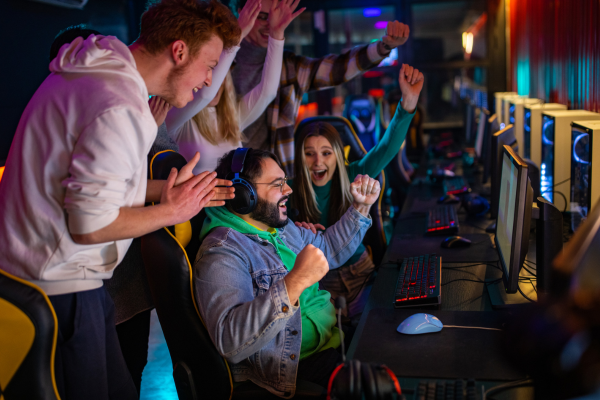 Gamers cheering in celebration together surrounded by gaming stations