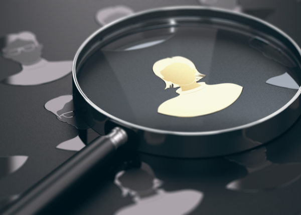 Magnifying glass hovering over a golden silhouette of a recruiter