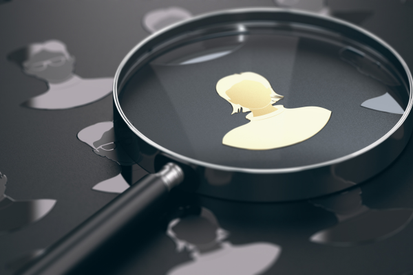 Magnifying glass hovering over a golden silhouette of a recruiter