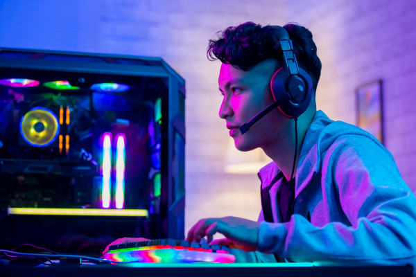 Man gaming with a gaming headset on and a gaming computer in the background