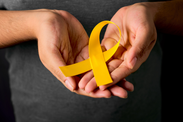 Open hands with a yellow ribbon