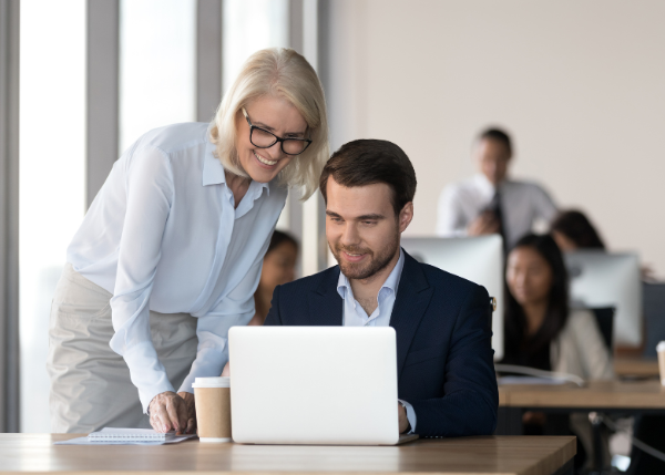 Two people working together looking at a laptop screen.