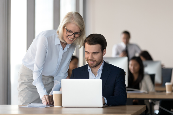 Two people working together looking at a laptop screen.